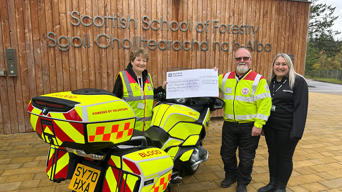 Three people standing with a bike and holding a cheque Three people standing with a bike and holding a cheque