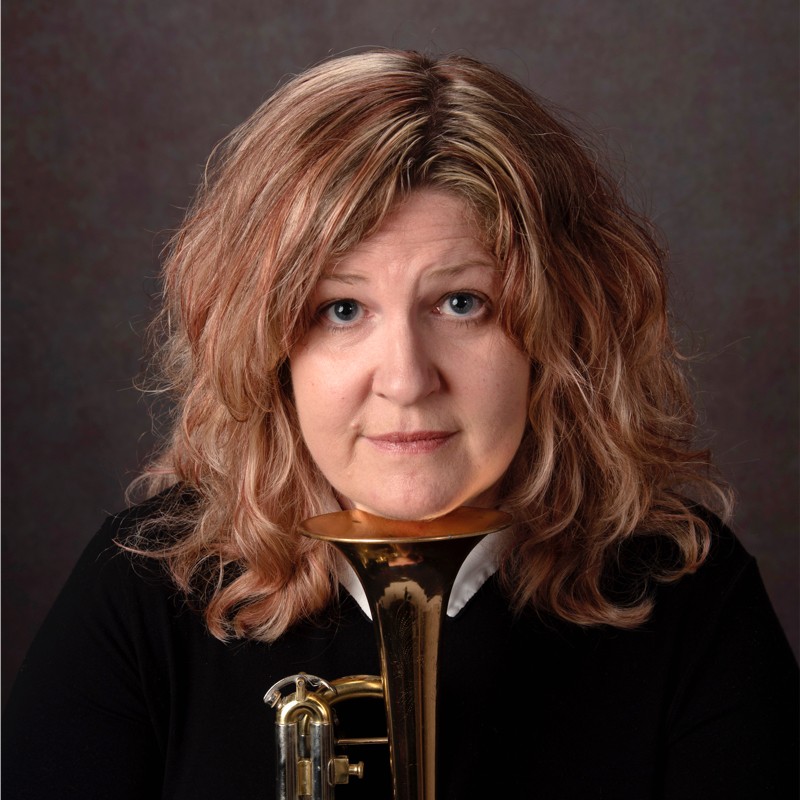 Pauline sitting with a musical instrument propped under their chin Pauline sitting with a musical instrument propped under their chin