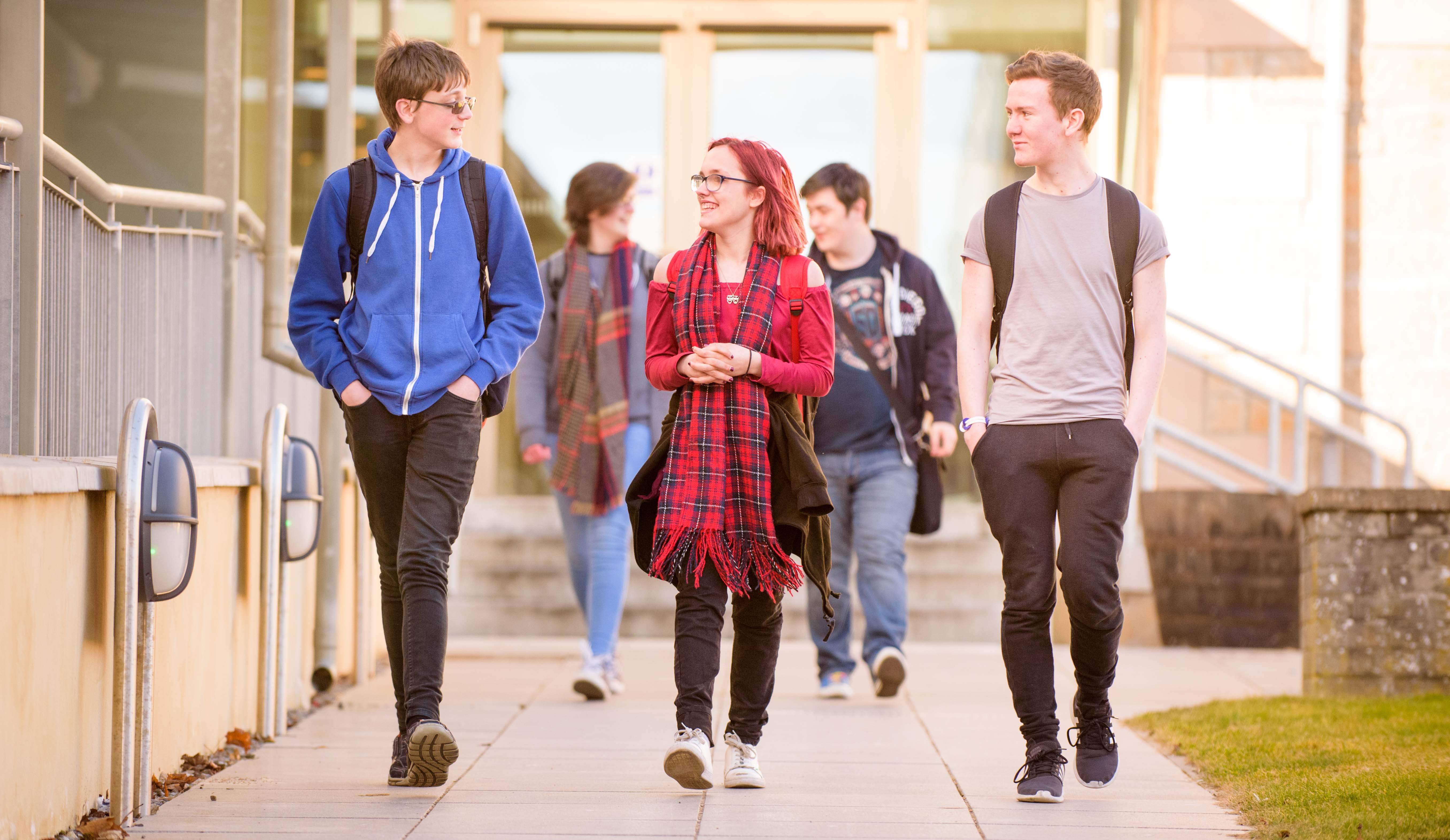 A group of students walking outside a university building A group of students walking outside a university building