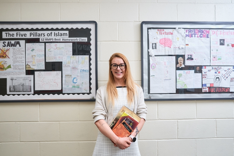 Eva Lovell in a school hallway holding books Eva Lovell in a school hallway holding books